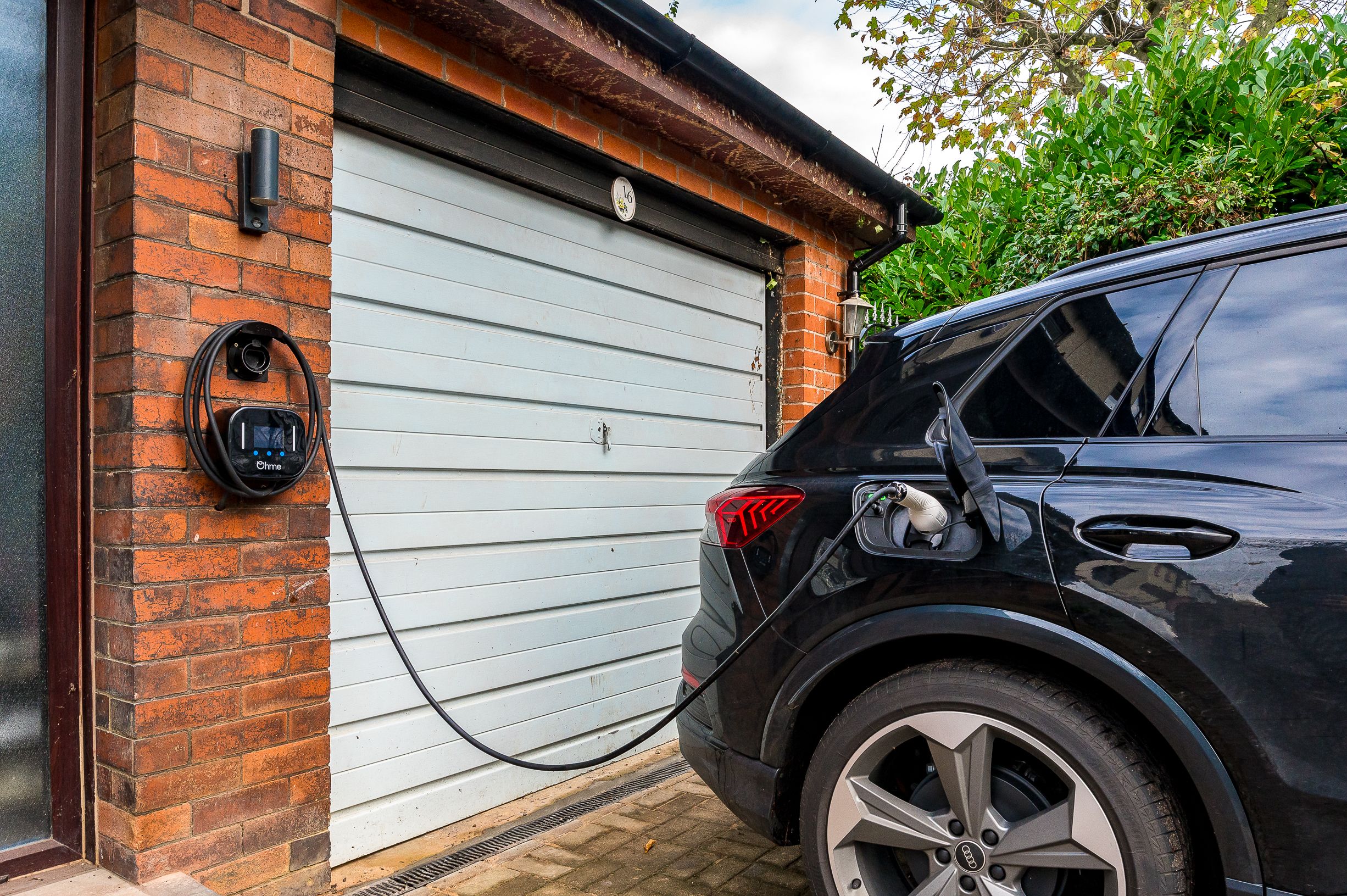 An Electric Vehicle Charger on the front of a retrofitted home plugged into a car