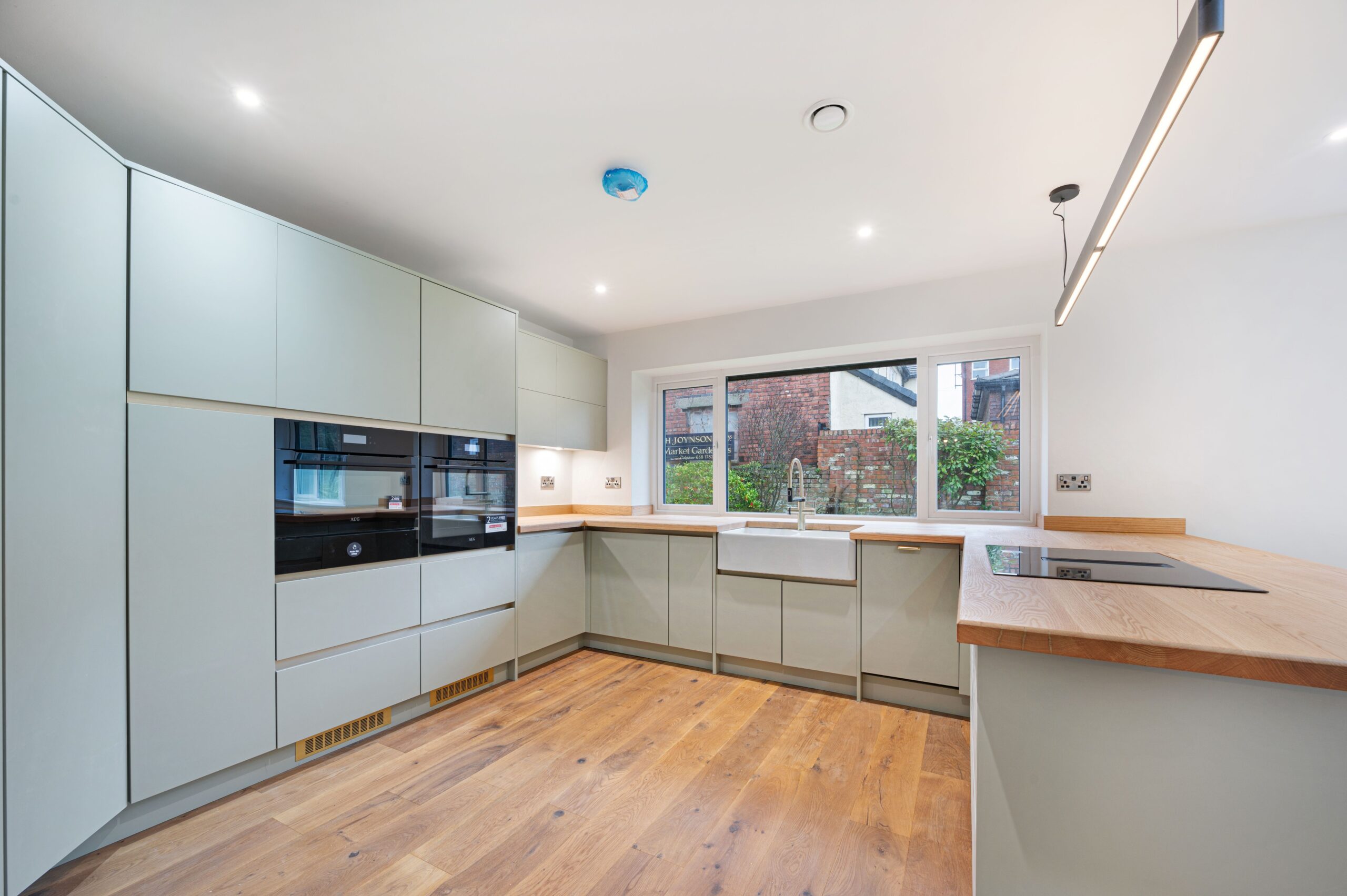 The kitchen inside the retrofitted bungalow that shows built in sage cupboards, a double oven/microwave with built in underfloor heating and wall insulation