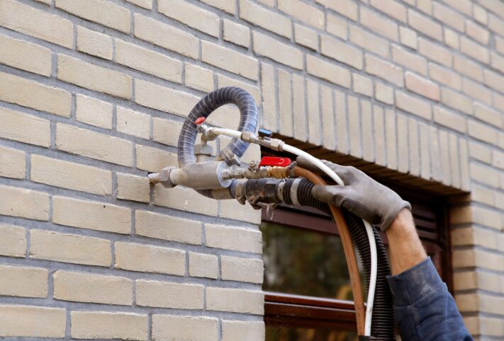 A worker pumping wall insulation into a wall